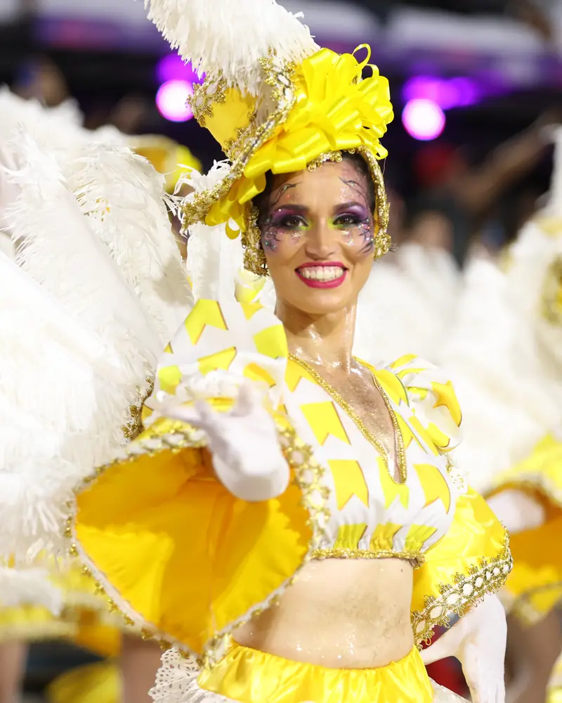 Natalia Ferrer sonriendo con traje amarillo y tocado de plumas blancas en el Carnaval de Río