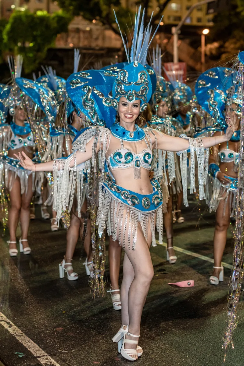 Naty desfilando con traje azul y plateado, entre las bailarinas de su ala, en la avenida de noche
