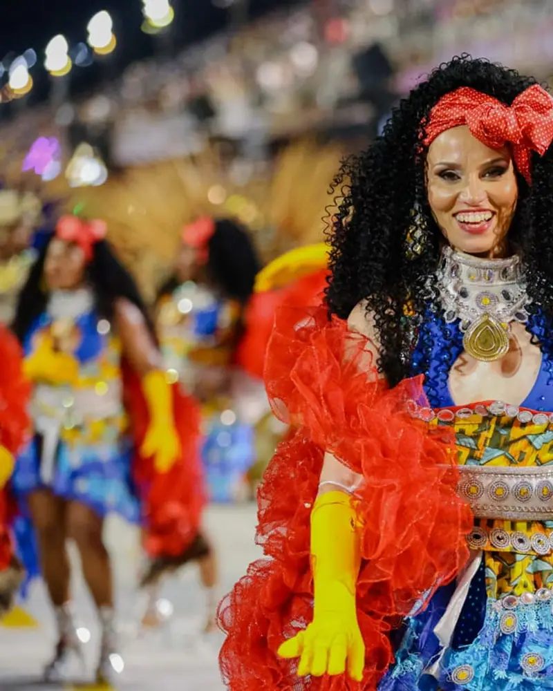 Naty sonriendo con traje azul y rojo en pleno desfile