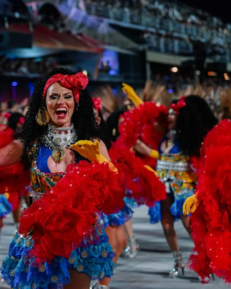 Naty con boa roja entre las bailarinas de la escola