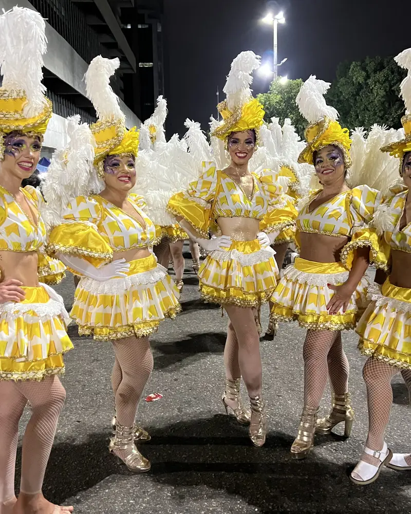 Bailarinas de samba con trajes amarillos y blancos avanzando por la avenida