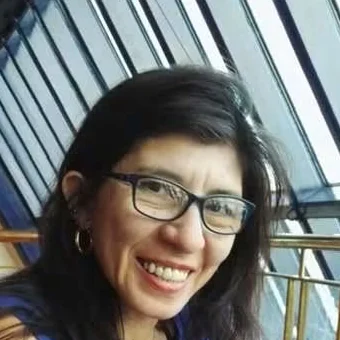 Retrato de Mirta, sonriendo, con anteojos y remera azul